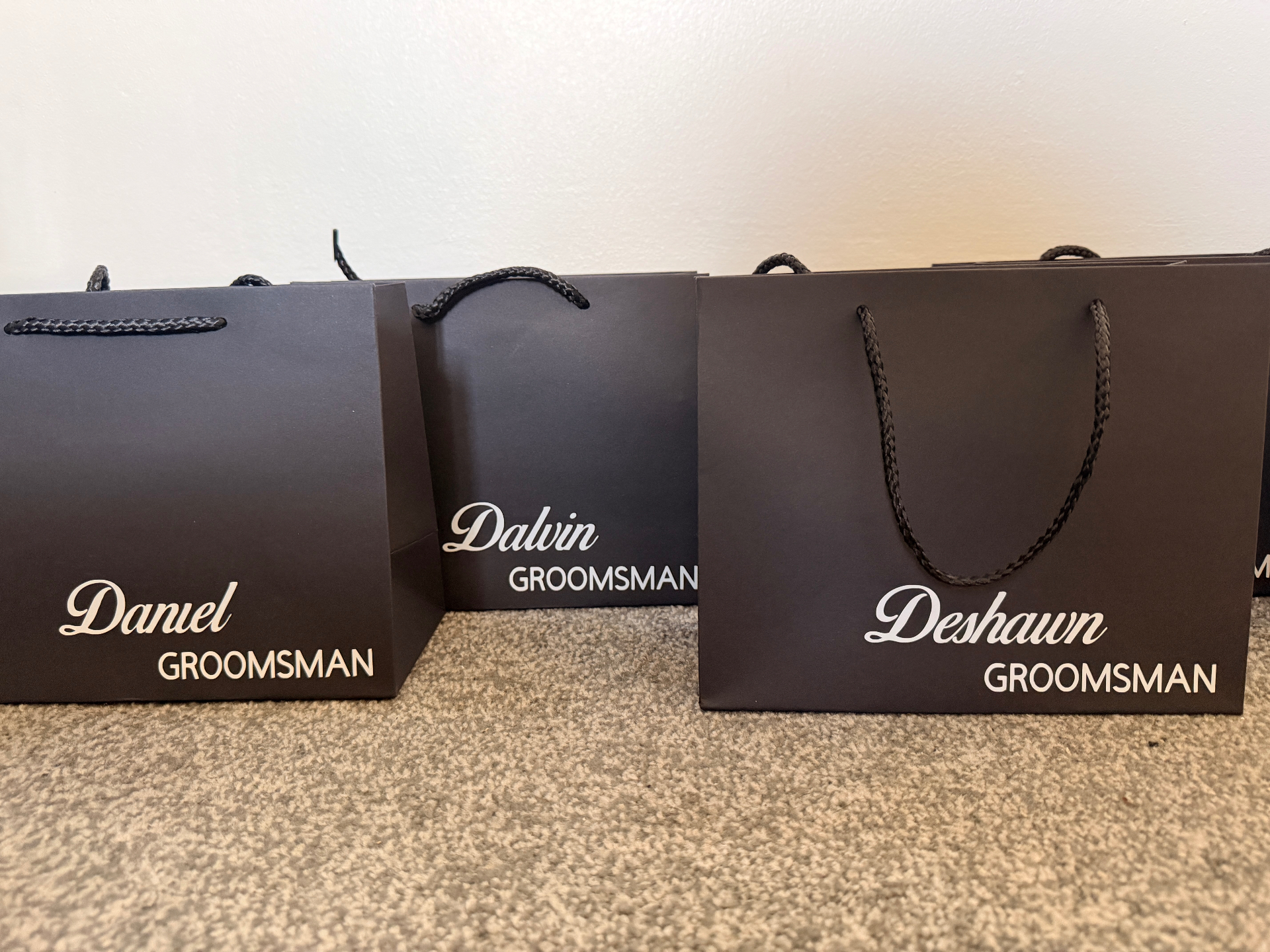 Personalised matte black groomsman gift bags with white script names